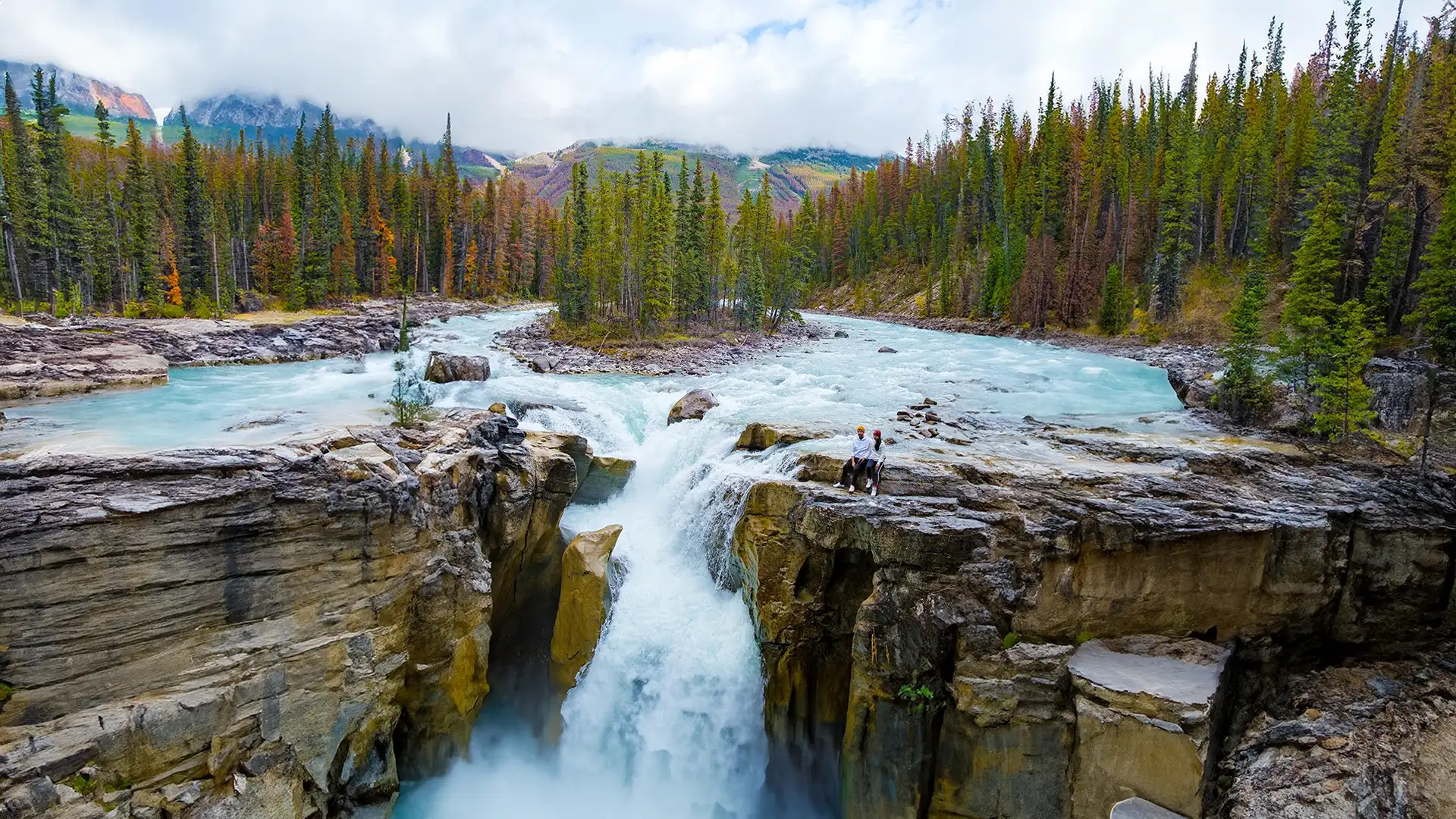 Sunwapta Falls, Jasper-Nationalpark, Kanada. Die kanadischen Rocky Mountains im Herbst. Ein paar Männer und Frauen, die die Sunwapta Falls besuchen und am Rand des Wasserfalls stehen